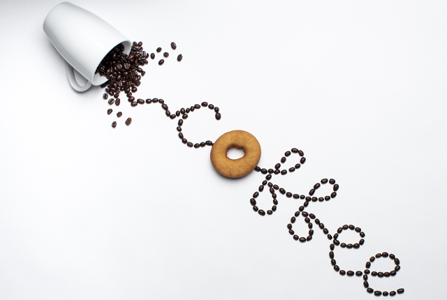 Photography student artistic photo of the word coffee written with a spilt cup of coffee beans.