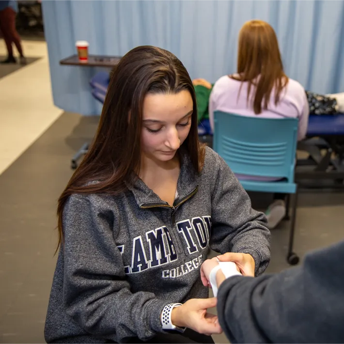 A student wrapping another student's hand during a simulator patient session.