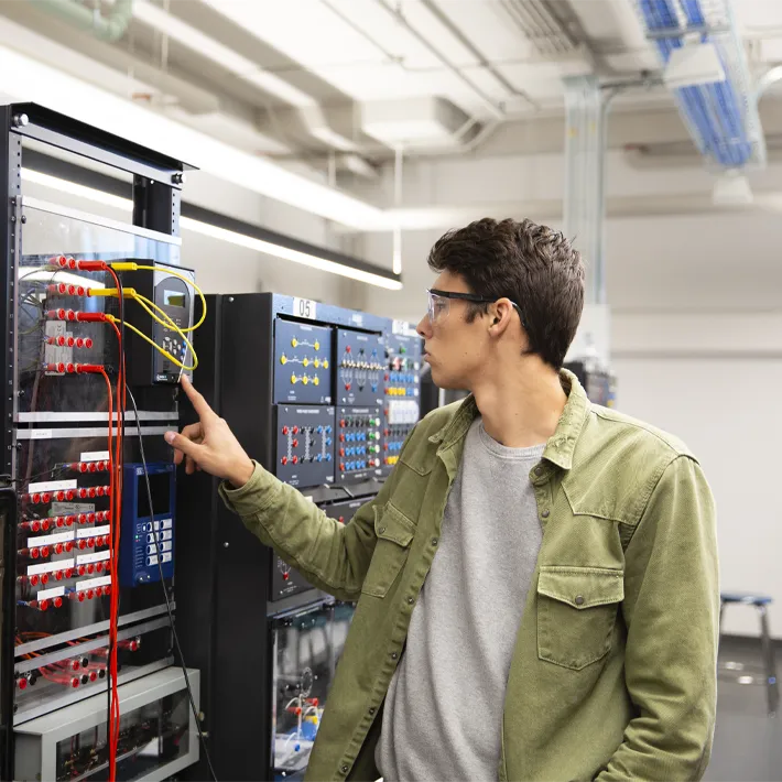 Student in electrical room pressing buttons.