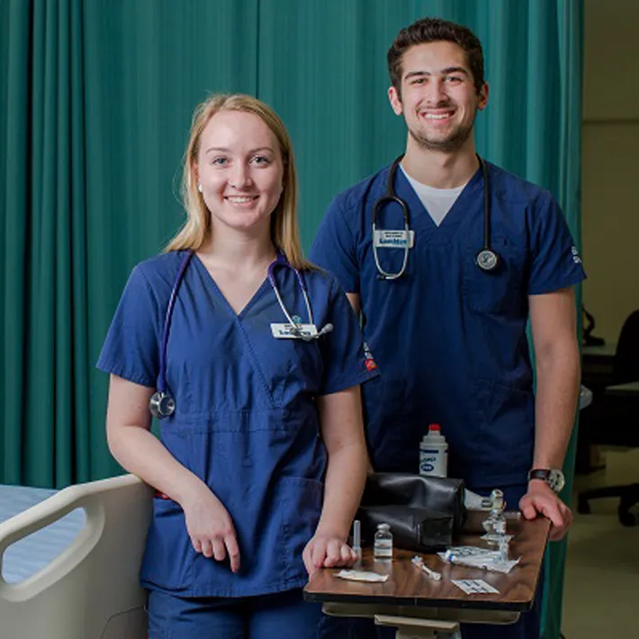 Nursing students posing for photo in simulation lab room.