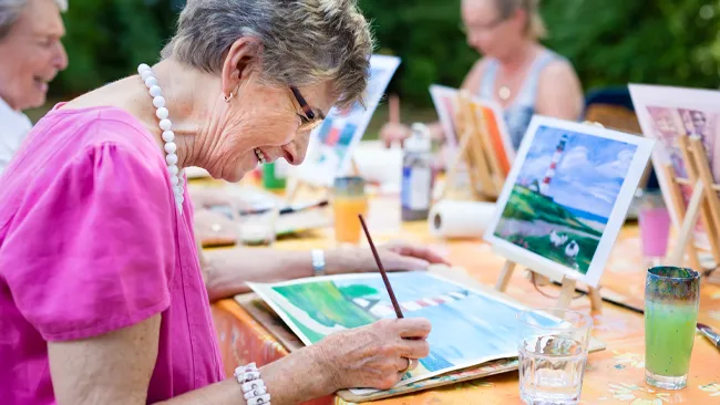 Older women painting outside as a recreation therapy activity.