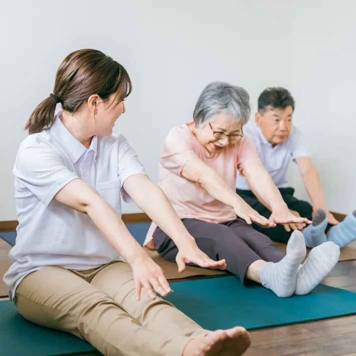A photo of professional recreation therapist stretching with older patients.