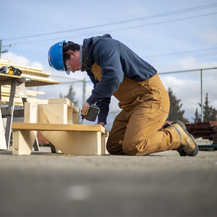 Student working on building steps outside.