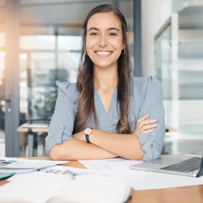 Young professional sitting at desk with paper surrounding her.