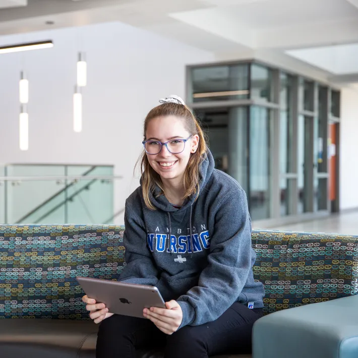 Student sitting in common areas on her ipad.