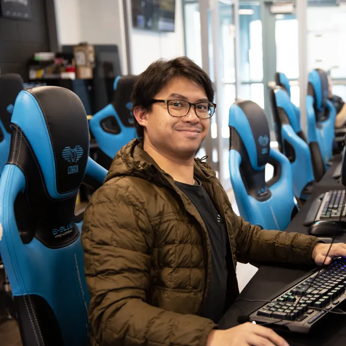 Student in esport arena sitting at gaming computer.