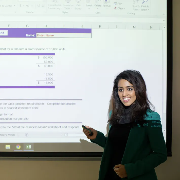 Student presenting information on projector screen.