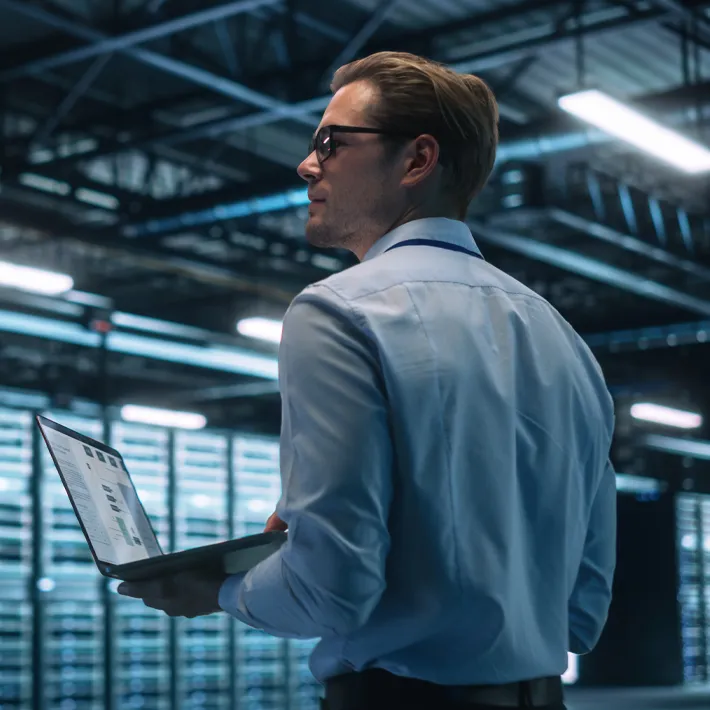 A male Information Technology Professional standing in a Server Farm Cloud Computing and Cyber Security Maintenance room