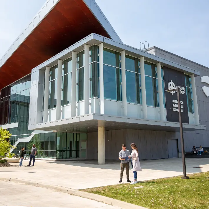 Students sitting on a bench outside in front of Lambton College