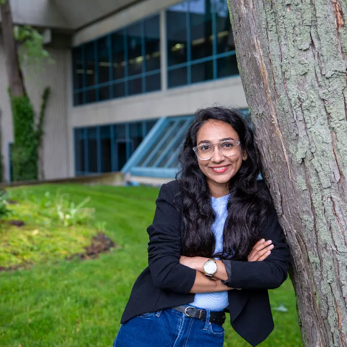 Student leaning against a tree outside lambton college