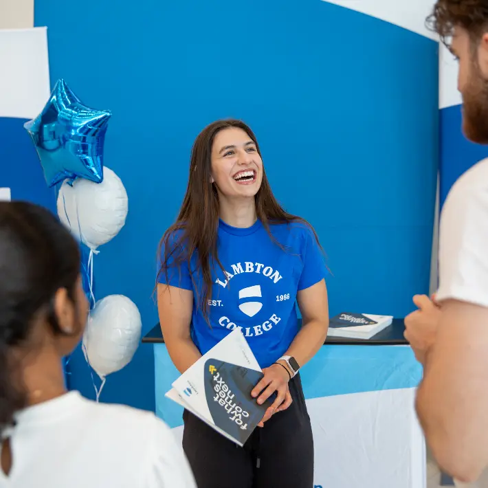 Recruiter standing in front of lambton banners talking to people