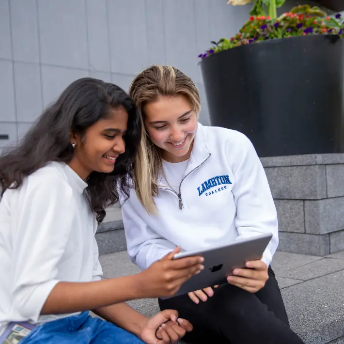 Students outside looking at an IPad