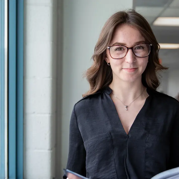 Student standing in the hallway, reading a book