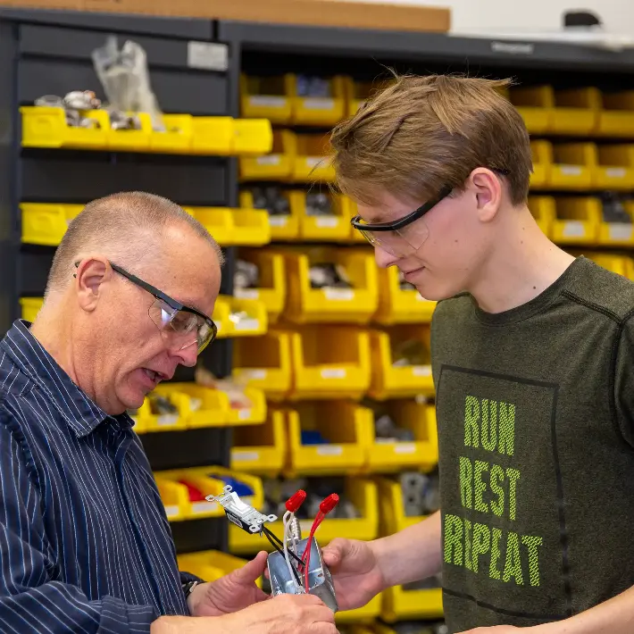 Residential electrical dual credit student with teacher in shop.