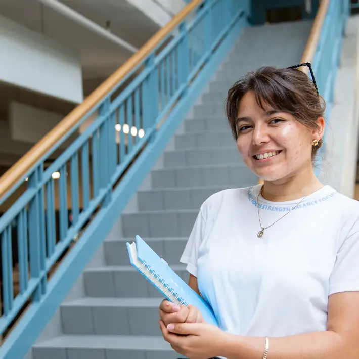 student-hallway Student standing at staircase with books