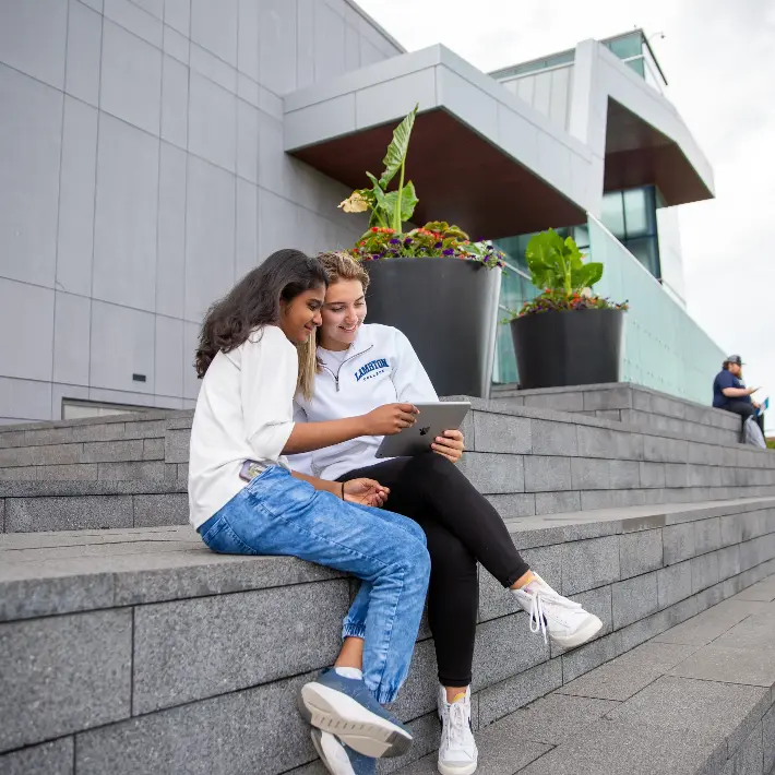 Two students sitting outdoors on the steps