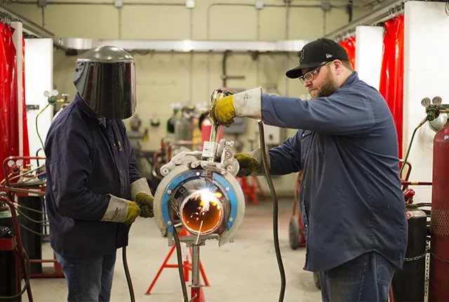 A photo of two steamfitter students using tools in the lab.